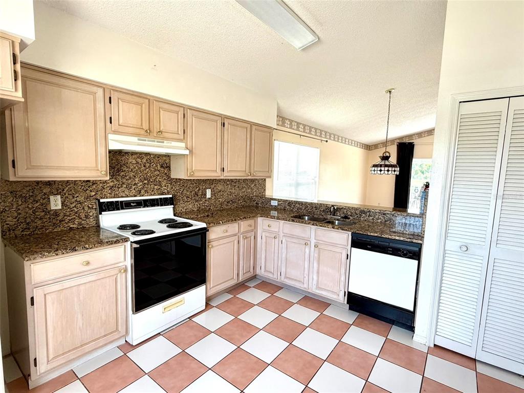 A kitchen features light wood cabinets, granite countertops, and a checkered tile floor — 2705 CHATHAM CIRCLE, KISSIMMEE, FL