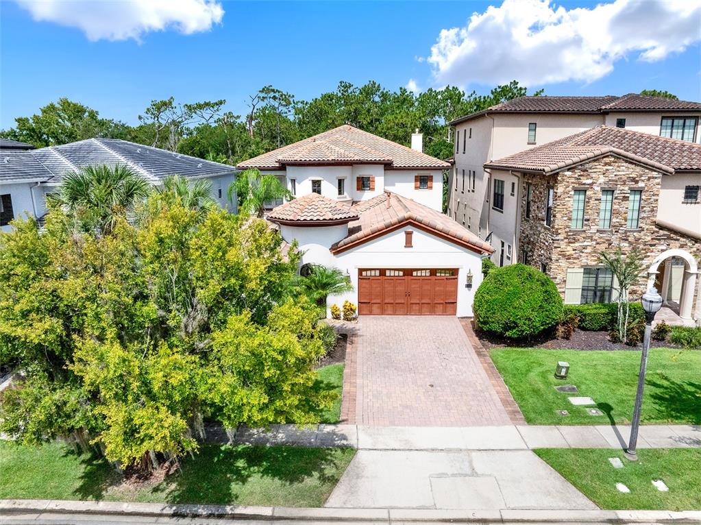 An aerial view shows a two-story house with a tiled roof and a brick driveway — 1284 GRAND TRAVERSE PARKWAY, REUNION, FL