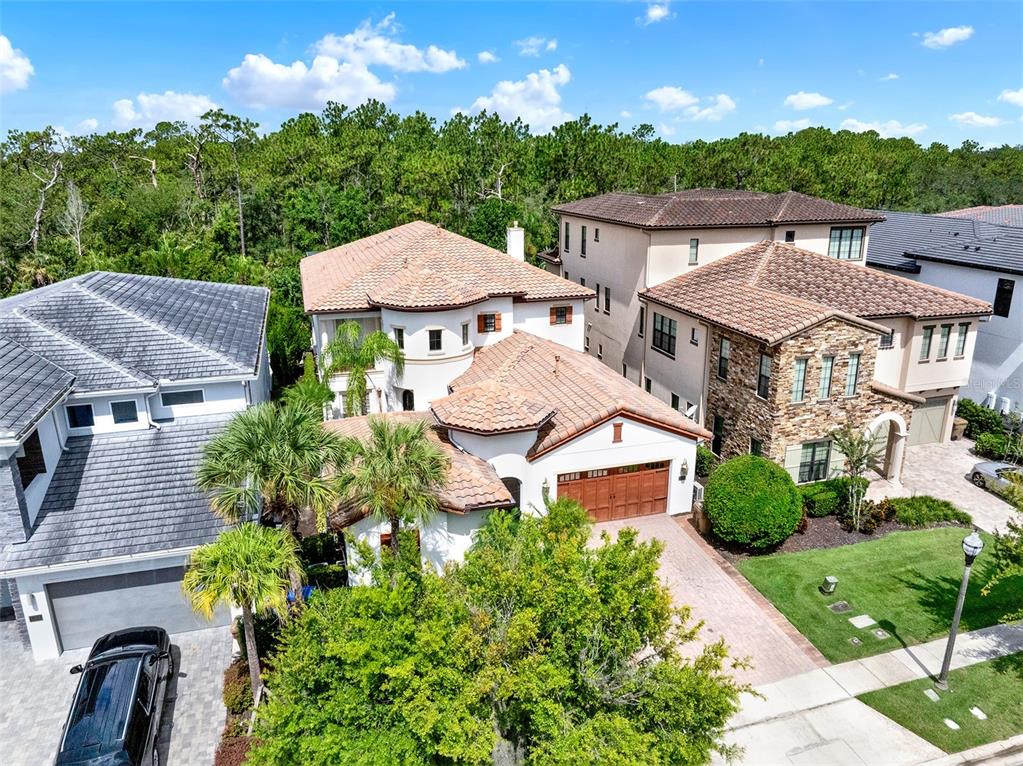 An aerial view shows a multi-story house with a tile roof and a paved driveway — 1284 GRAND TRAVERSE PARKWAY, REUNION, FL