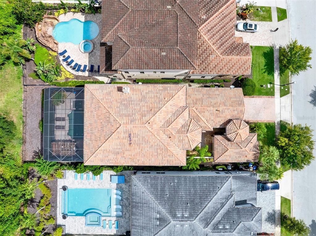 An aerial view shows three houses with tiled roofs, swimming pools, and screened-in lanais — 1284 GRAND TRAVERSE PARKWAY, REUNION, FL