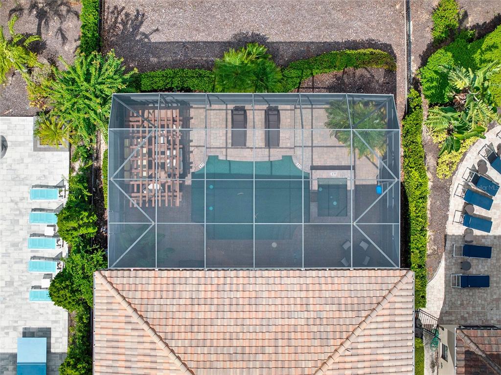 An aerial view shows a screened-in pool and patio area behind a tiled roof house — 1284 GRAND TRAVERSE PARKWAY, REUNION, FL