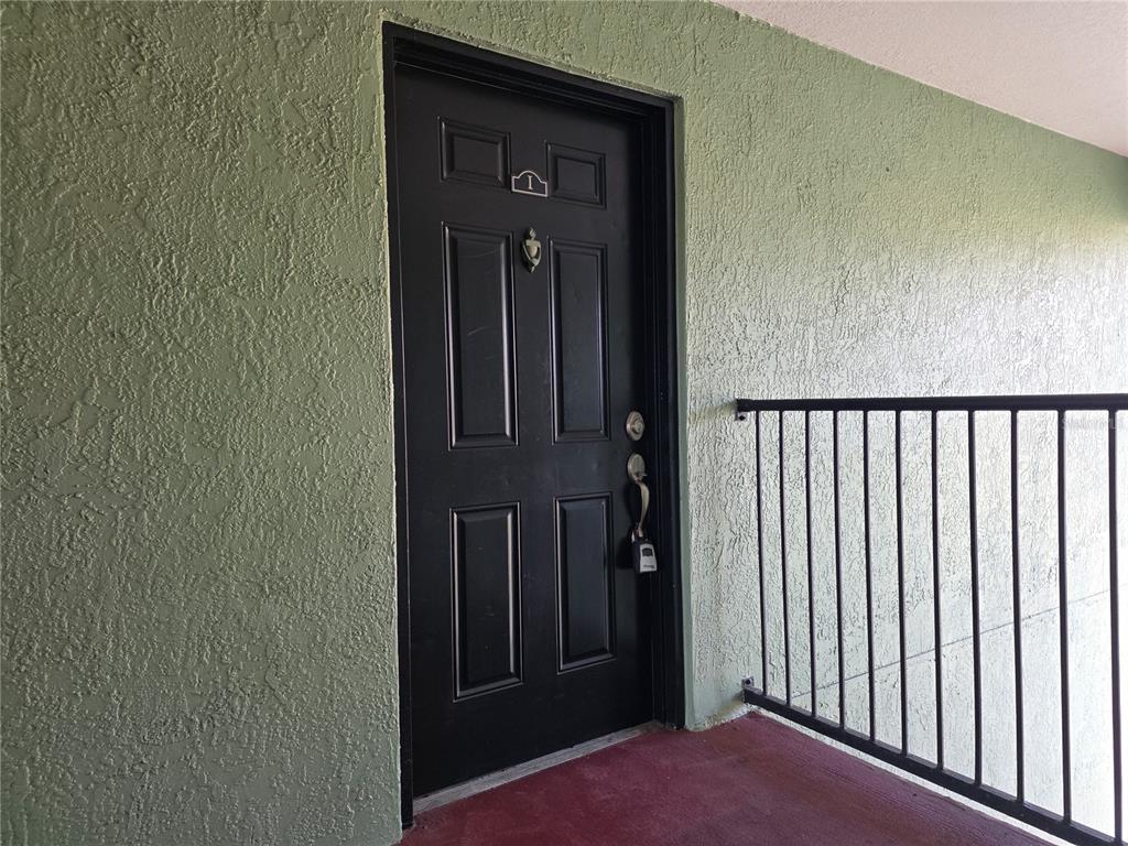 A black front door with a padlock is set into a textured green exterior wall — 2031 DIXIE BELLE DRIVE UNIT 2031I, ORLANDO, FL