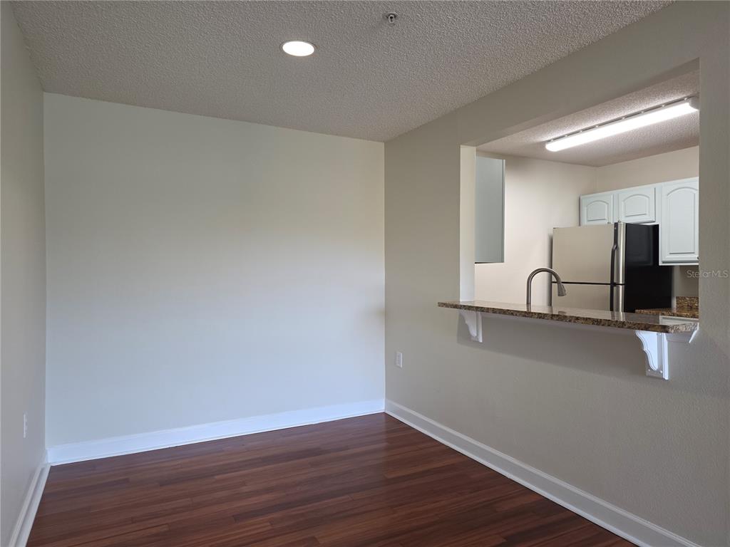 A dining area with wood flooring features a breakfast bar opening into a kitchen — 2031 DIXIE BELLE DRIVE UNIT 2031I, ORLANDO, FL