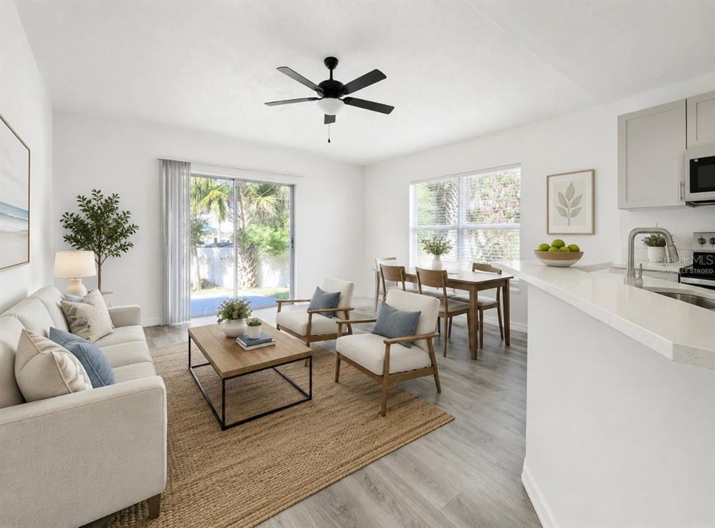 This living and dining area features white walls, light wood flooring, and a sliding door — 210 FAIRFIELD DRIVE, SANFORD, FL