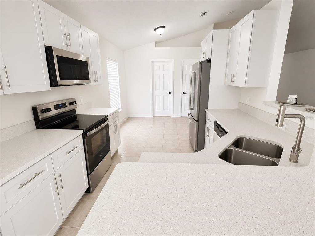 A kitchen features white cabinets, stainless steel appliances, and light-colored countertops — 210 FAIRFIELD DRIVE, SANFORD, FL