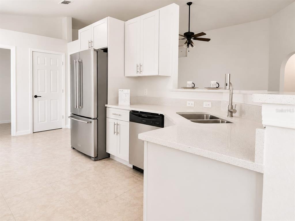 A kitchen features white cabinets, stainless steel appliances, and light-colored countertops — 210 FAIRFIELD DRIVE, SANFORD, FL