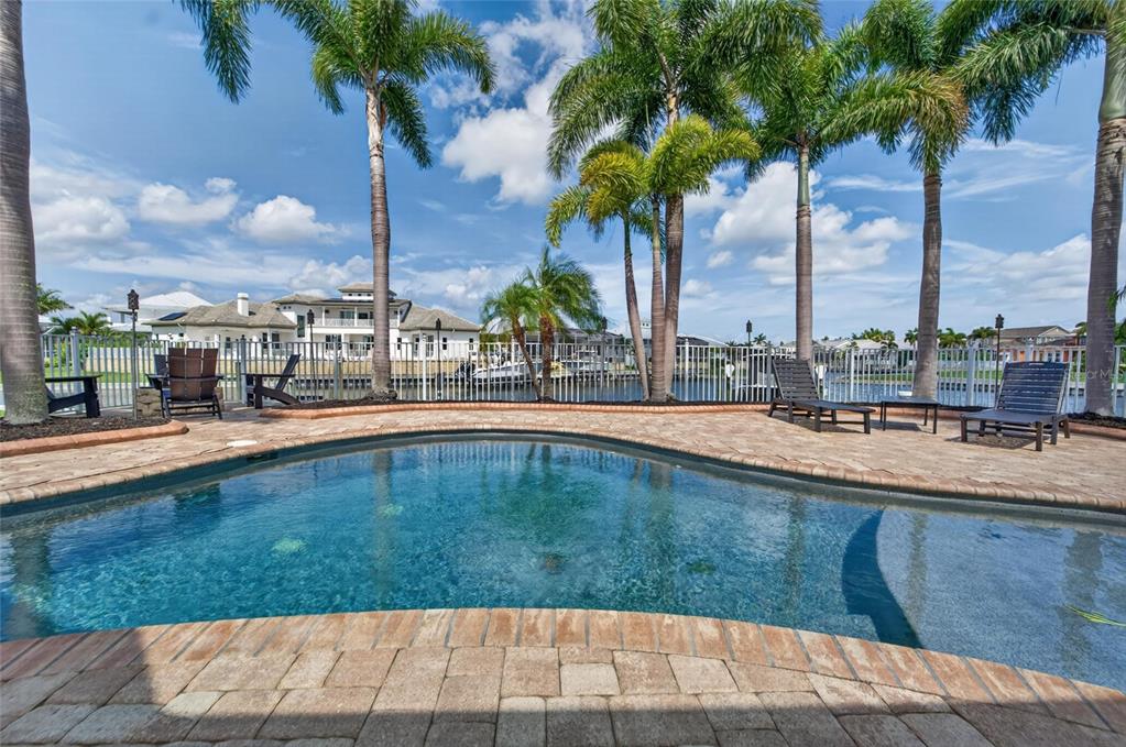 A swimming pool with a brick paver deck overlooks a canal with palm trees — 5722 SEA TROUT PLACE, APOLLO BEACH, FL
