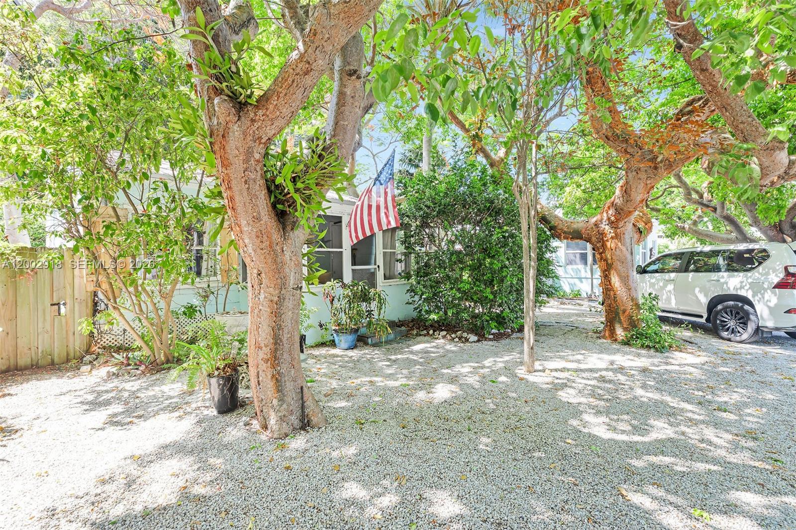 A gravel driveway leads to a light blue house shaded by large trees — 140 Tavern Dr, Tavernier FL 33070, TAVERNIER, FL