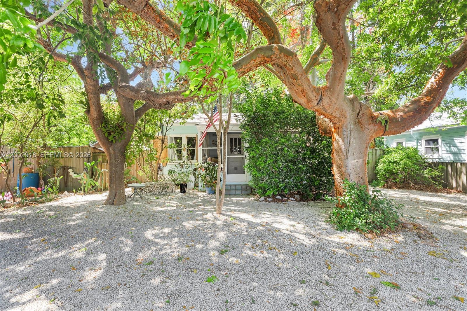 A small house with a white door and American flag sits behind large trees — 140 Tavern Dr, Tavernier FL 33070, TAVERNIER, FL