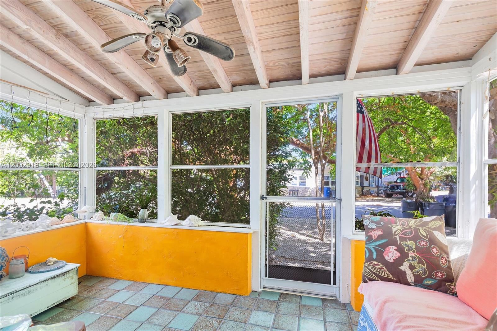 A screened-in porch features yellow walls, a tiled floor, a ceiling fan, and large windows — 140 Tavern Dr, Tavernier FL 33070, TAVERNIER, FL