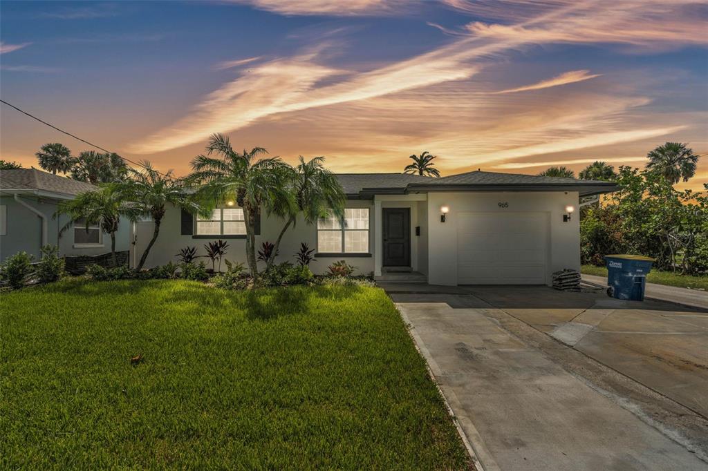 A single-story house with a white exterior, a garage, and a palm-filled front yard at sunset — 965 BRUCE AVENUE, CLEARWATER BEACH, FL