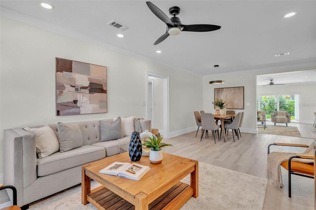 A bright living room features a gray sofa, wooden coffee table, and an adjacent dining area — 965 BRUCE AVENUE, CLEARWATER BEACH, FL