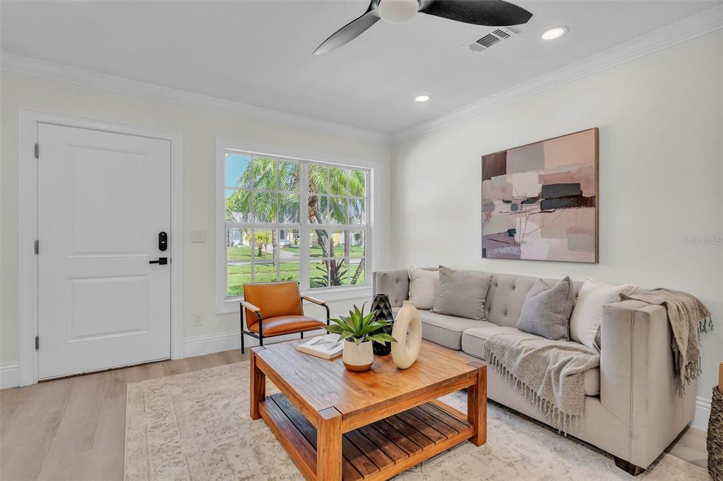 A living room features a gray tufted sofa, a wooden coffee table, and a leather chair — 965 BRUCE AVENUE, CLEARWATER BEACH, FL