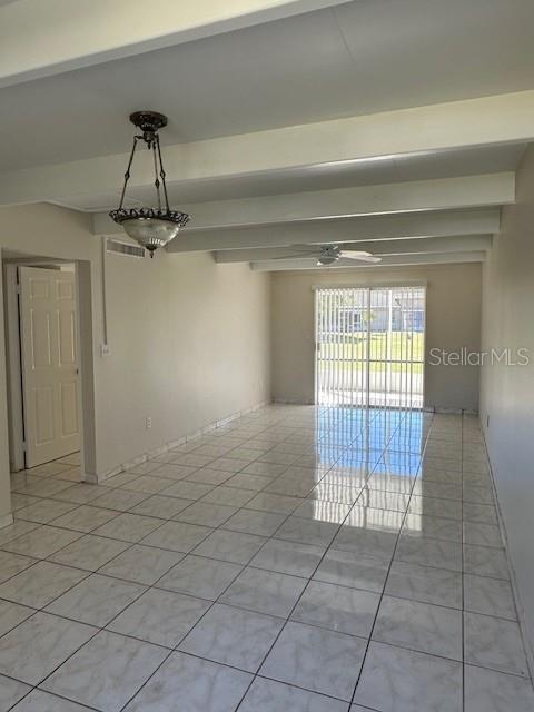 An empty room features white tile floors, exposed ceiling beams, and a hanging pendant light — 2709 CLUB CIRCLE, LAKE WALES, FL