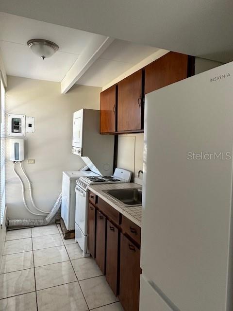 A kitchen features wood cabinets, a white refrigerator, a stove, and a stacked laundry unit — 2709 CLUB CIRCLE, LAKE WALES, FL