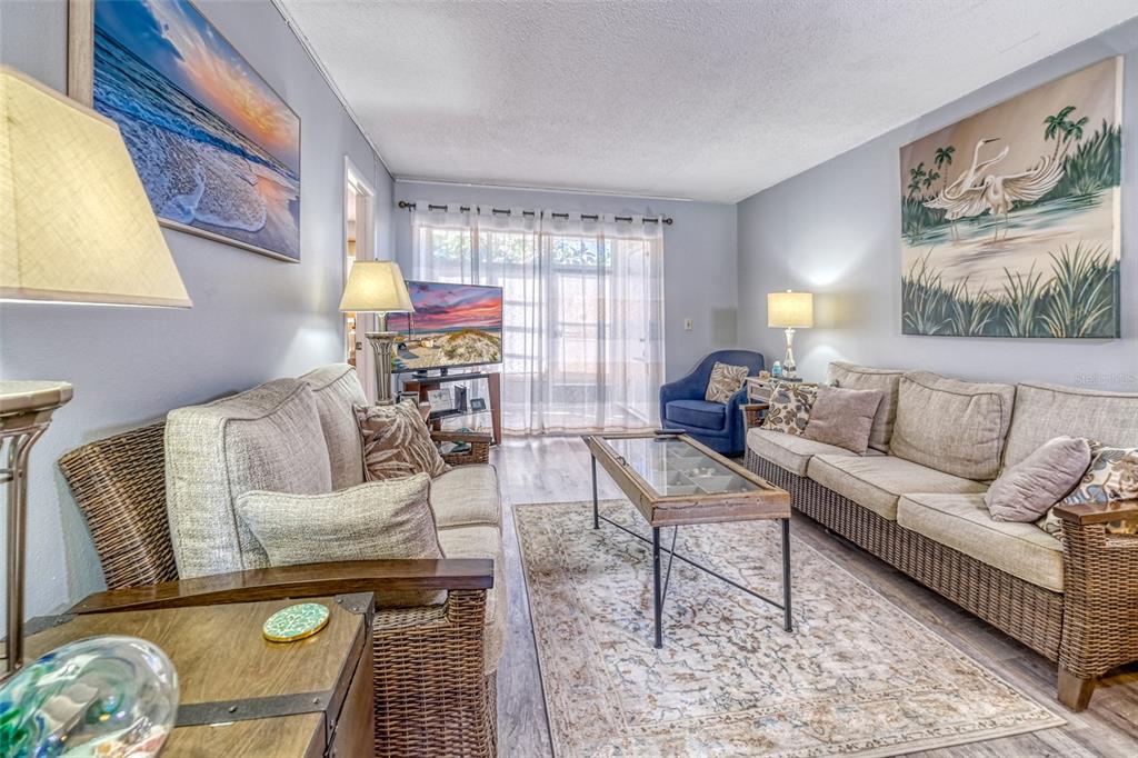 A living room features two wicker sofas, a glass-top coffee table, and coastal-themed wall art — 13714 MISSION OAKS BOULEVARD UNIT 13714, SEMINOLE, FL