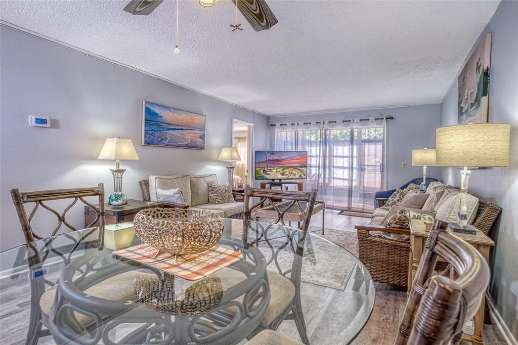 A living room and dining area feature a glass-topped table, wicker furniture, and light flooring — 13714 MISSION OAKS BOULEVARD UNIT 13714, SEMINOLE, FL