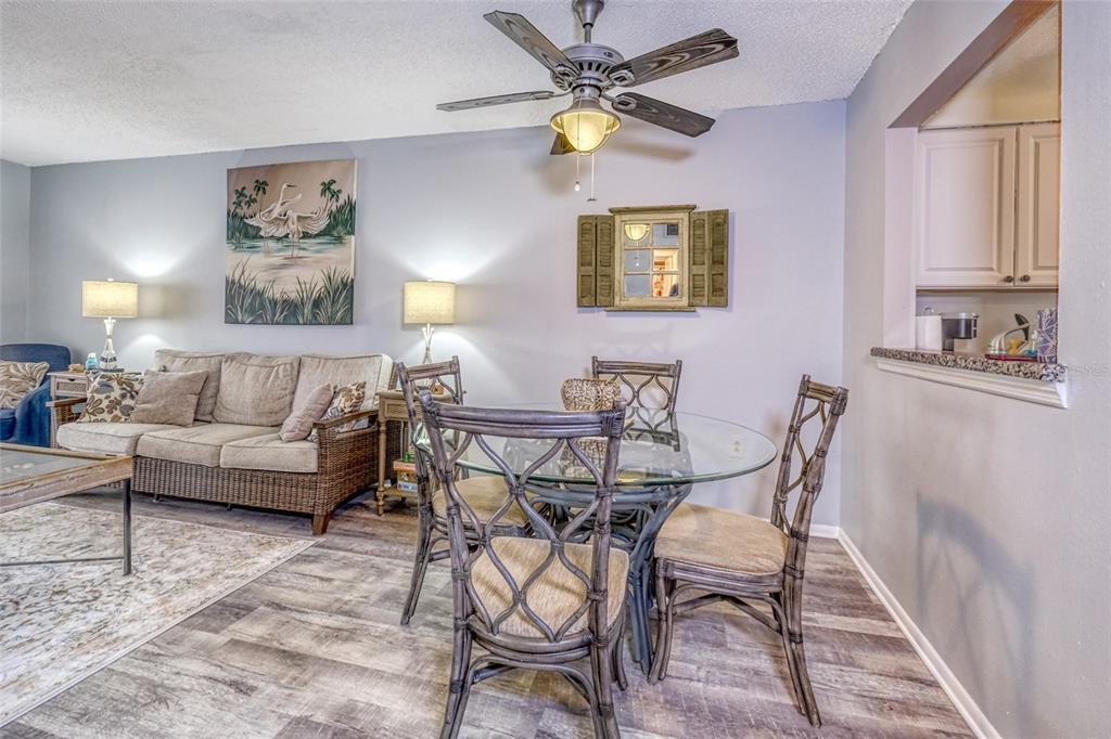 A dining area with a glass table and rattan chairs sits beside a living room — 13714 MISSION OAKS BOULEVARD UNIT 13714, SEMINOLE, FL