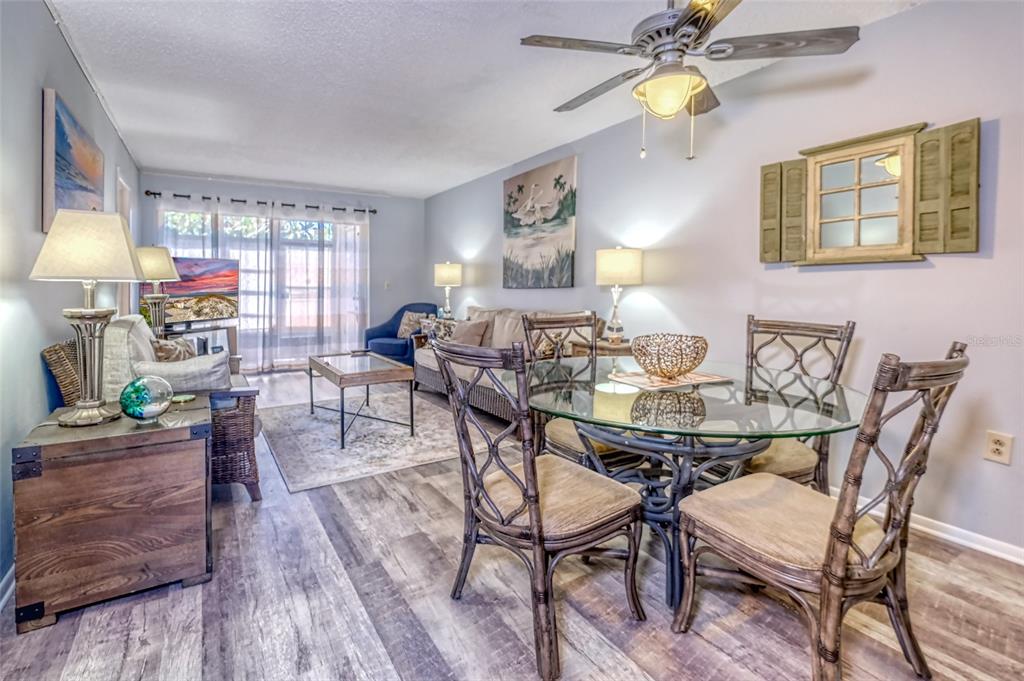 A living and dining area features wood-look flooring, a glass-topped table, and a ceiling fan — 13714 MISSION OAKS BOULEVARD UNIT 13714, SEMINOLE, FL