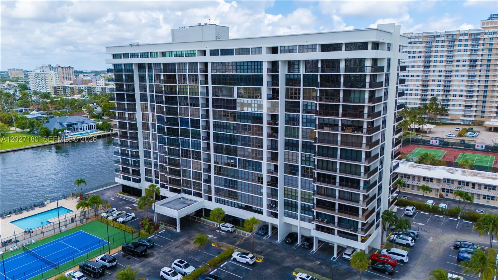 An aerial view shows a multi-story residential building with balconies, a pool, and tennis courts — 2017 S Ocean Dr # 1104, Hallandale Beach FL 33009, HALLANDALE BEACH, FL