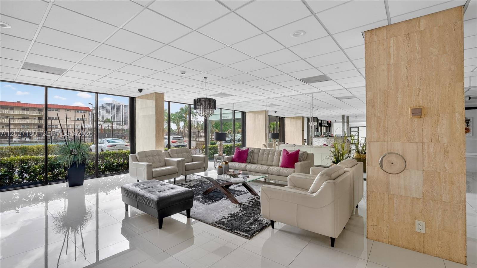 A modern lobby features white tile floors, leather seating, a glass coffee table, and floor-to-ceiling windows — 2017 S Ocean Dr # 1104, Hallandale Beach FL 33009, HALLANDALE BEACH, FL