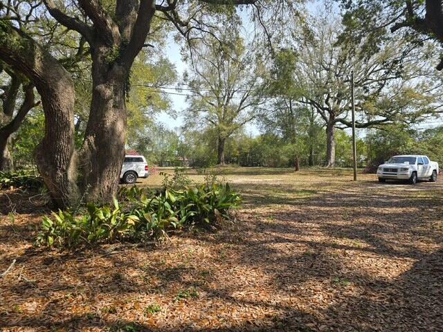 A gravel lot with large trees and two parked pickup trucks — 4643 Keyser Lane, FL 32571, FL