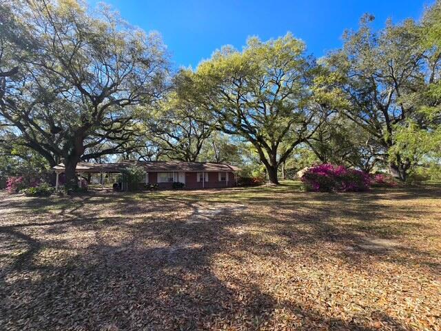 A single-story brick house with a carport sits on a large, tree-shaded lot — 4643 Keyser Lane, FL 32571, FL