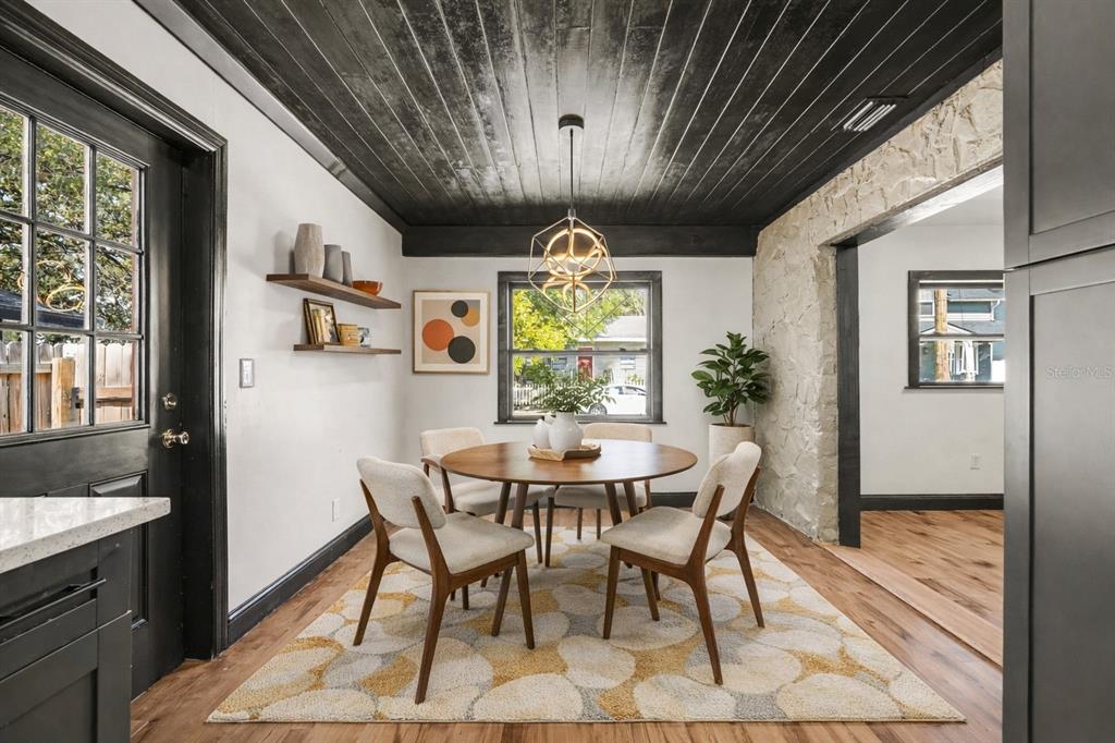 A dining room features a black wood-plank ceiling, stone wall, and a round wooden table — 1221 E EMMA STREET, TAMPA, FL