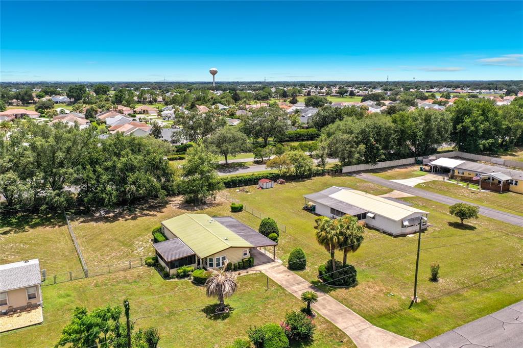 An aerial view shows two single-story houses with metal roofs on a grassy lot — 8233 COUNTY ROAD 109B, LADY LAKE, FL
