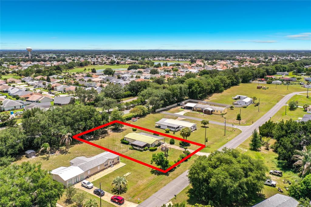 An aerial view shows a single-story house with a metal roof on a large lot — 8233 COUNTY ROAD 109B, LADY LAKE, FL