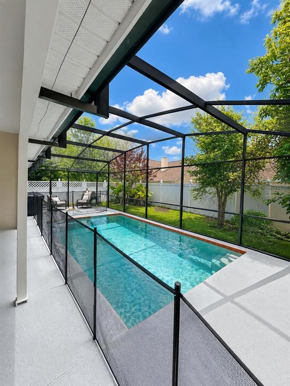 A rectangular swimming pool is enclosed by a black screen cage and a safety fence — 2144 CROSSHAIR CIRCLE, ORLANDO, FL