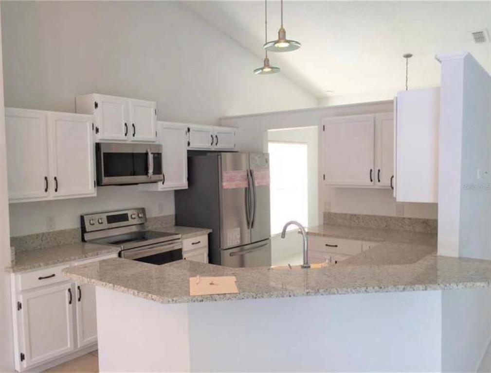 A kitchen with white cabinets, granite countertops, stainless steel appliances, and a breakfast bar — 2144 CROSSHAIR CIRCLE, ORLANDO, FL