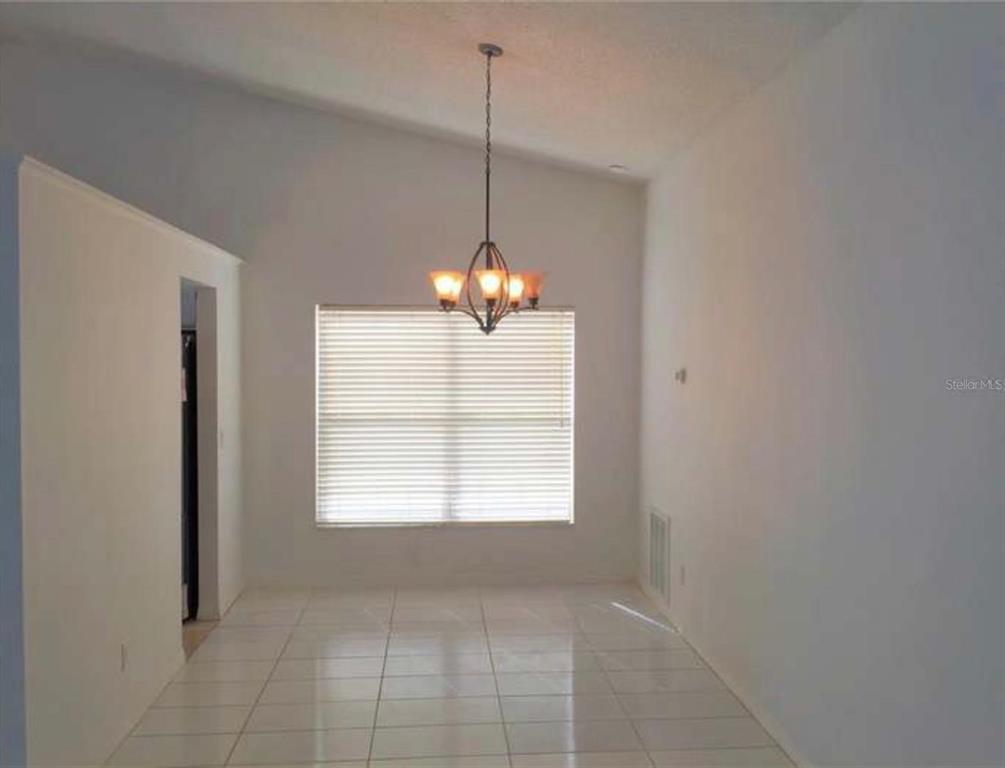 A dining area features white tile flooring, a vaulted ceiling, and a hanging chandelier — 2144 CROSSHAIR CIRCLE, ORLANDO, FL