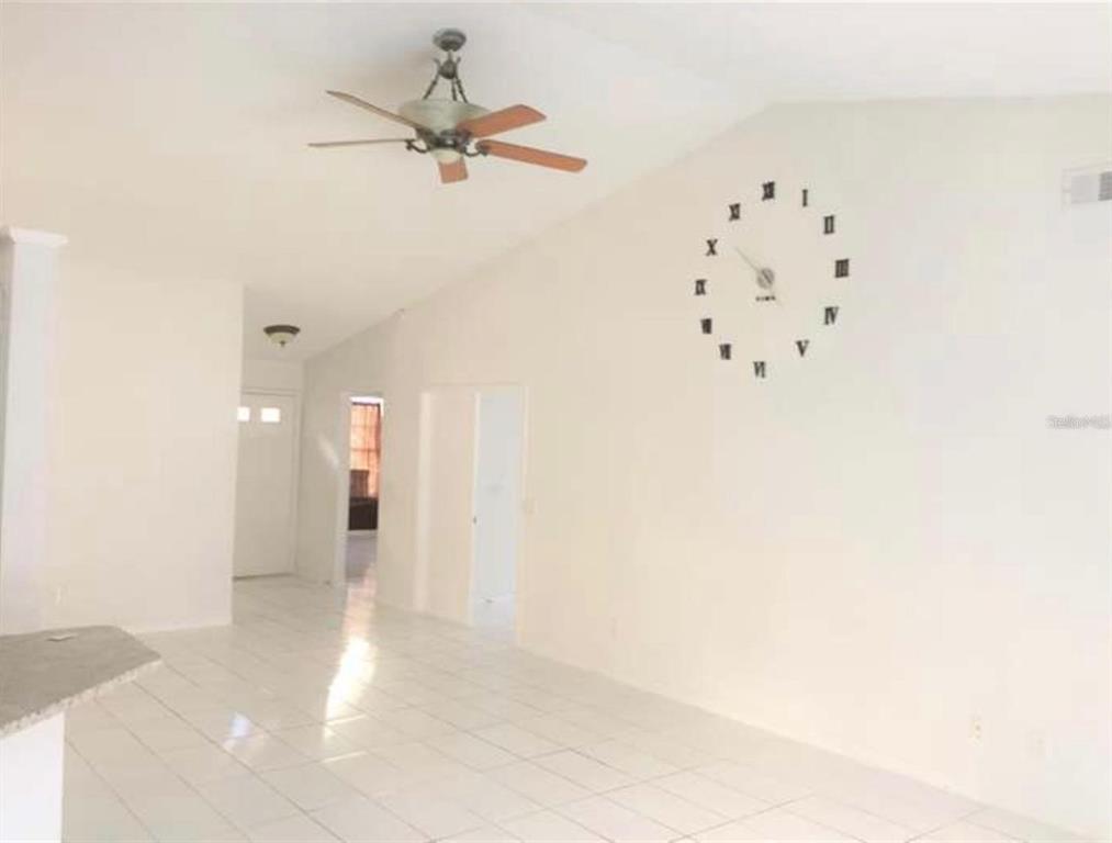 A bright, tiled living area features a vaulted ceiling, a ceiling fan, and a wall clock — 2144 CROSSHAIR CIRCLE, ORLANDO, FL