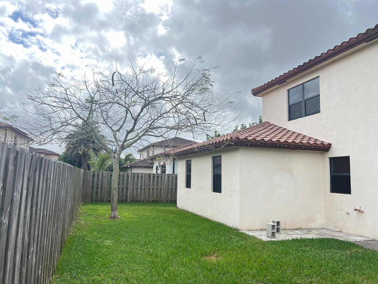 A backyard features a bare tree, a wooden fence, and the exterior of a house — 191 SE 35th Ave, Homestead FL 33033, HOMESTEAD, FL