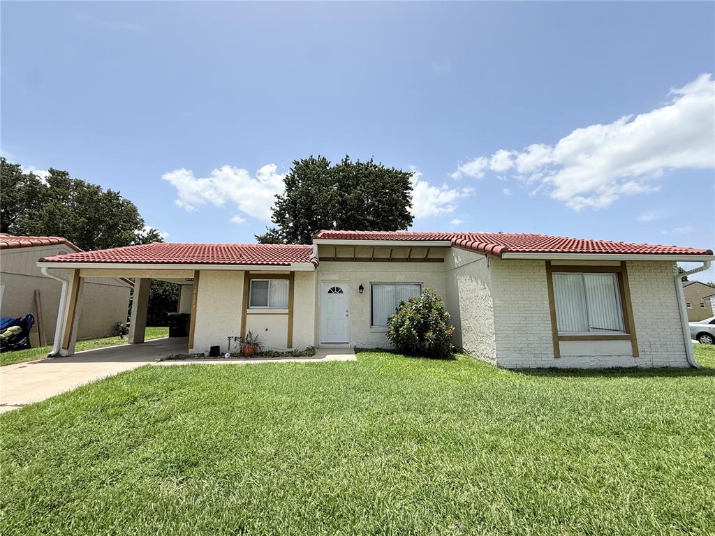 A single-story house with a red tile roof, white stucco exterior, and an attached carport — 10122 MASON DIXON CIRCLE, ORLANDO, FL