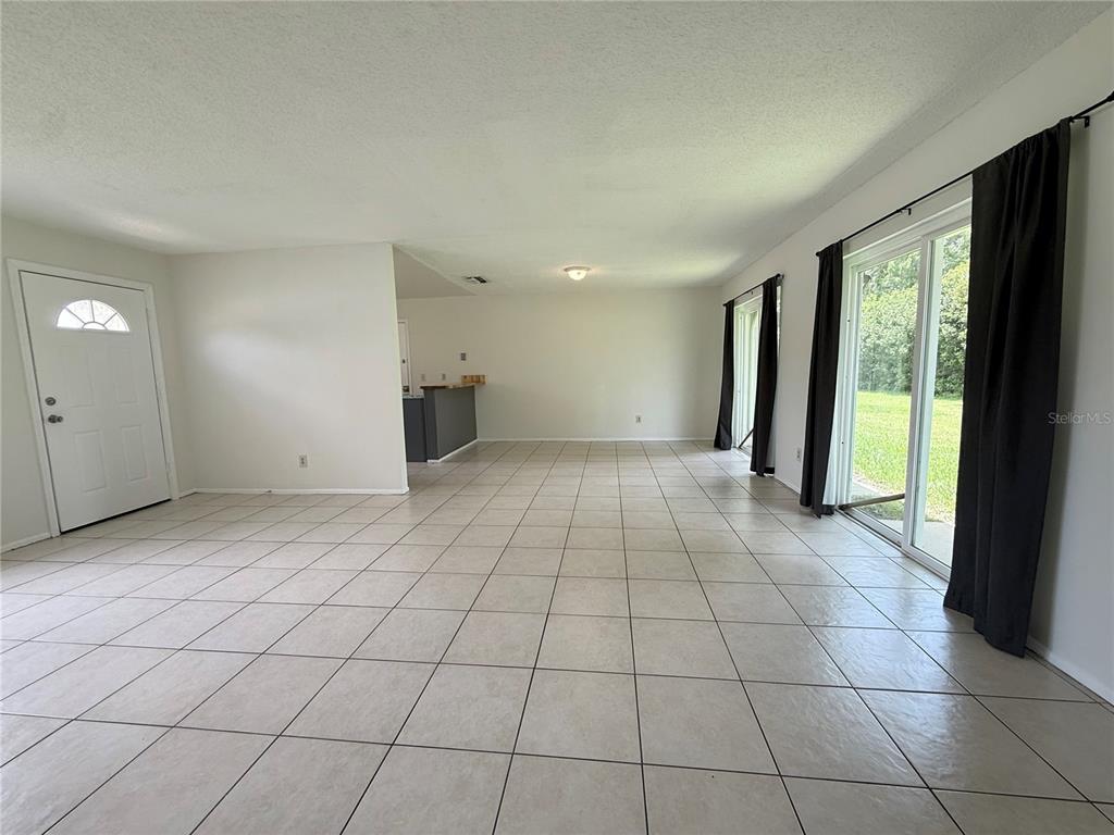 An open living area features light-colored tile flooring, white walls, and sliding glass patio doors — 10122 MASON DIXON CIRCLE, ORLANDO, FL