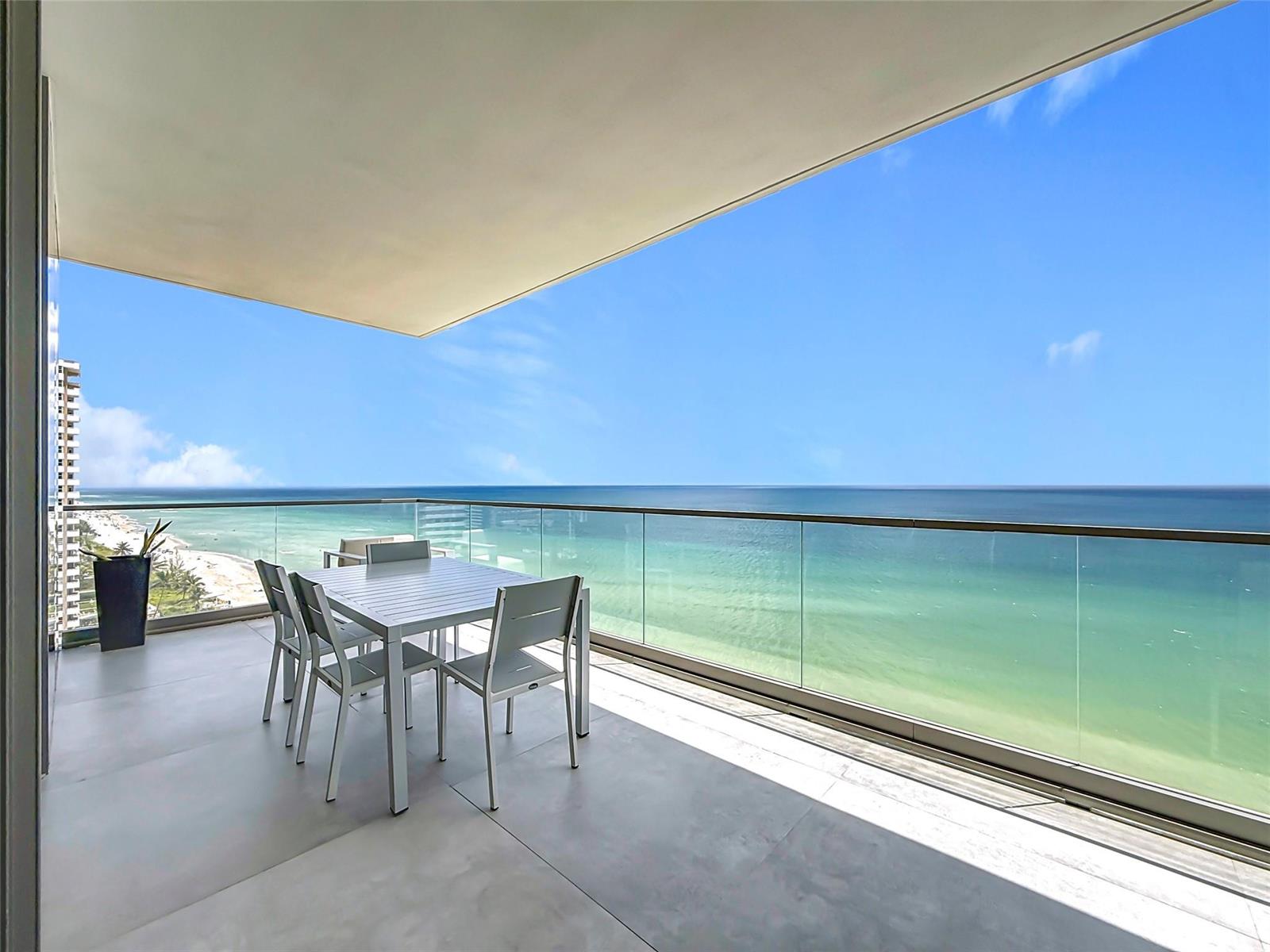 A balcony with a dining set overlooks the ocean and a sandy beach — 2000 S Ocean Drive # 12A, Hallandale Beach FL 33009, HALLANDALE BEACH, FL