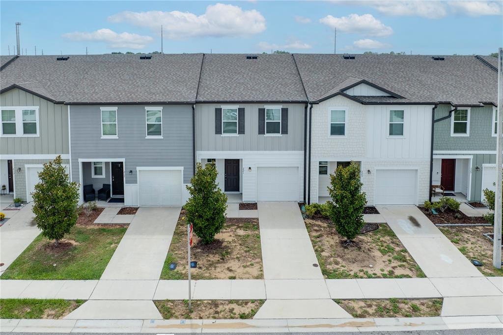 An exterior view of a row of modern townhouses with attached garages and small front yards — 221 MANDOVI STREET, DAVENPORT, FL