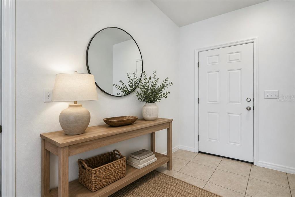 An entryway features a wooden console table, a round mirror, and a white front door — 221 MANDOVI STREET, DAVENPORT, FL
