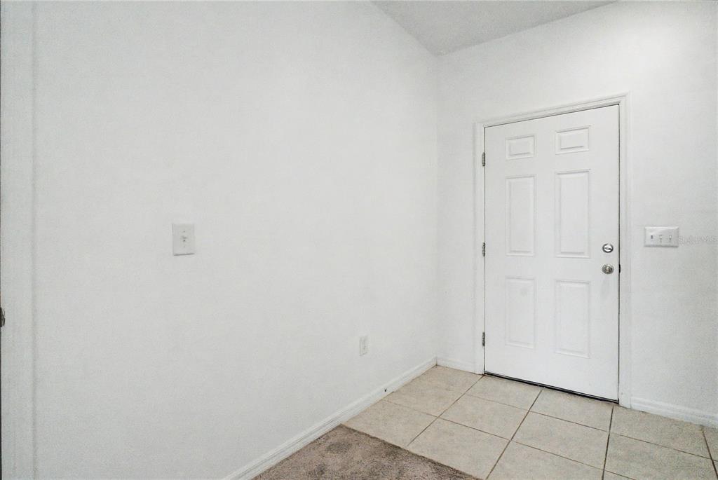 A white-walled entryway features a white door, tiled flooring, and a section of carpet — 221 MANDOVI STREET, DAVENPORT, FL