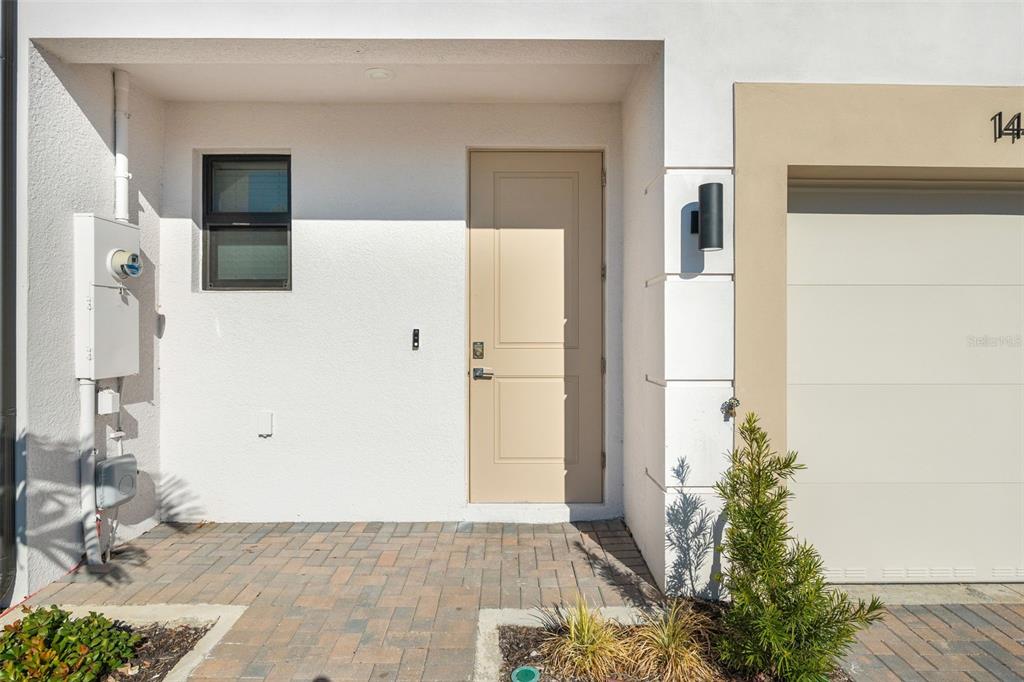 The exterior of a modern home features a beige door, a window, and a garage — 14515 STELLAR PLACE, LAKEWOOD RANCH, FL