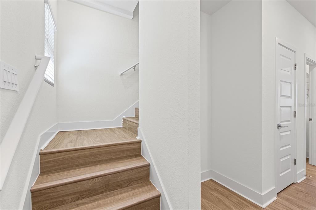 A staircase with wood-look steps and white walls leads to an upper level — 14515 STELLAR PLACE, LAKEWOOD RANCH, FL