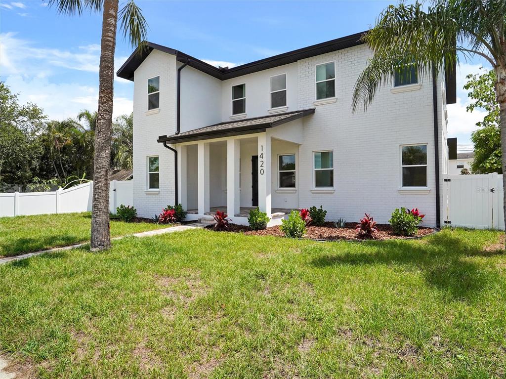 A two-story white brick house features a covered front porch and a grassy lawn — 1420 36TH AVENUE N, ST PETERSBURG, FL