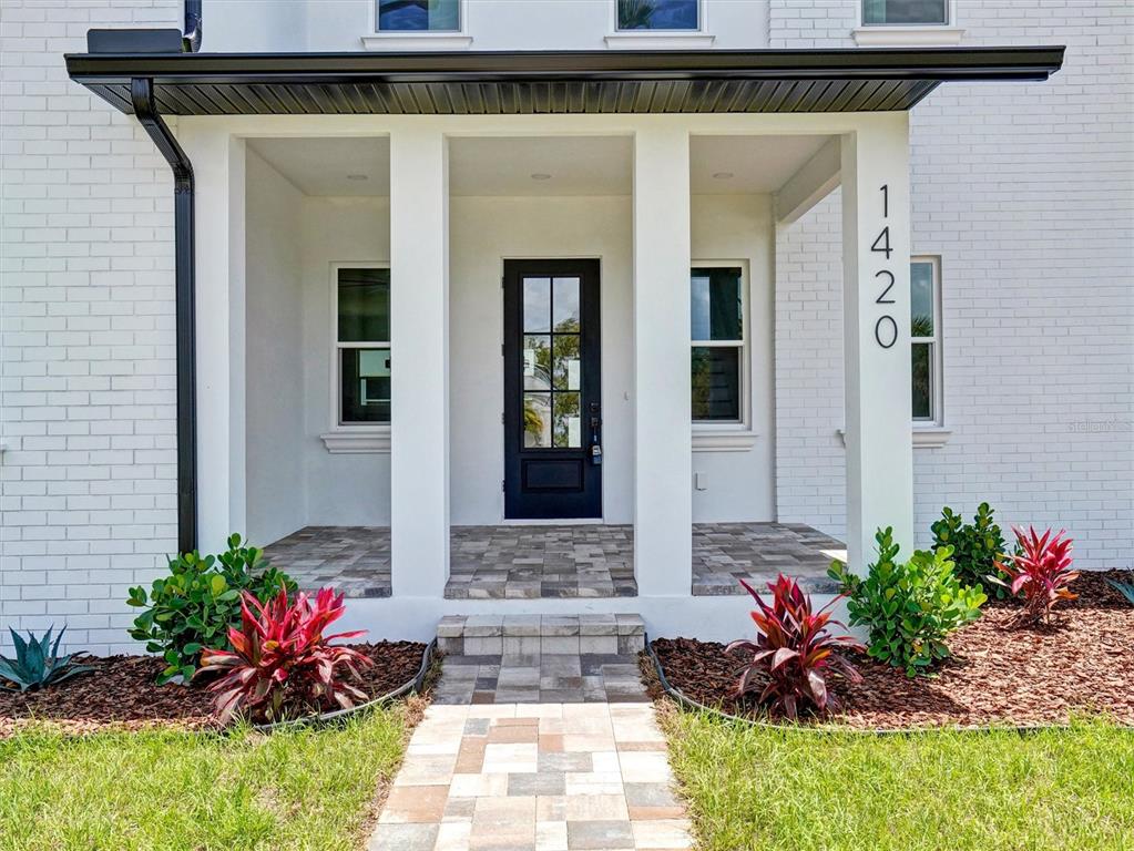 A white brick house exterior features a covered front porch with a dark door — 1420 36TH AVENUE N, ST PETERSBURG, FL
