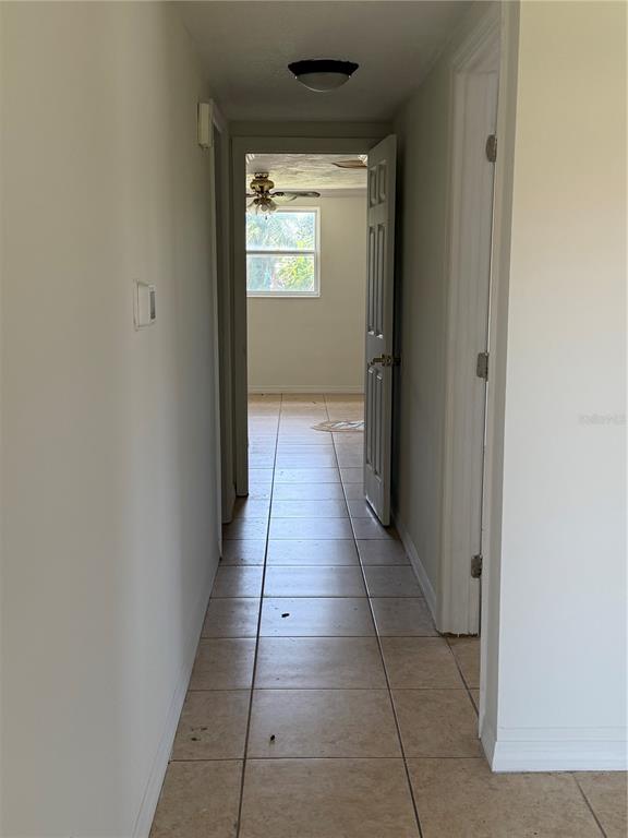 A hallway with light-colored tile flooring leads toward a doorway opening into another room — 4138 STAR ISLAND DRIVE, HOLIDAY, FL