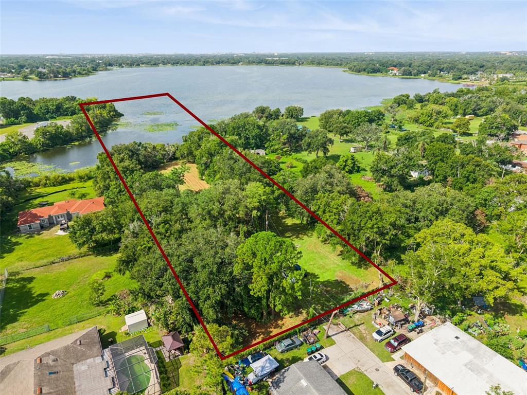 An aerial view shows a rectangular plot of land bordering a lake with dense trees — 3524 W ROBINSON STREET, ORLANDO, FL