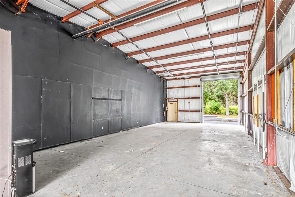 An industrial warehouse space features a concrete floor, black paneled walls, and an open bay — 7064 SAMPEY ROAD UNIT 1, GROVELAND, FL