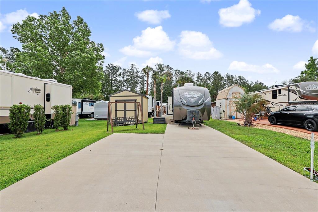 A concrete driveway sits between two parked recreational vehicles and a small storage shed — 2923 NE 104TH AVENUE, SILVER SPRINGS, FL
