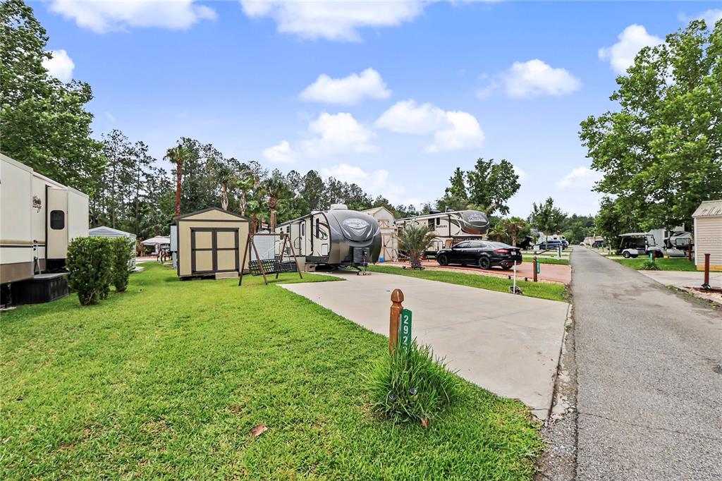 A concrete driveway leads to a parked recreational vehicle and a small storage shed — 2923 NE 104TH AVENUE, SILVER SPRINGS, FL